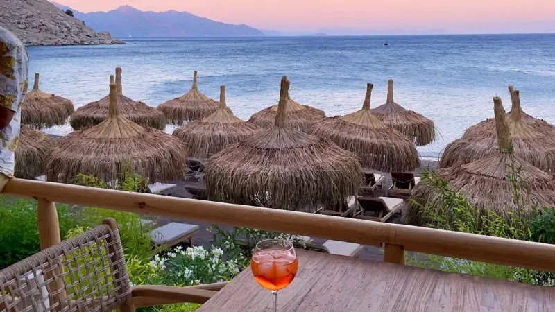 Sunset over the sea from a beach bar terrace, mountains in the distance