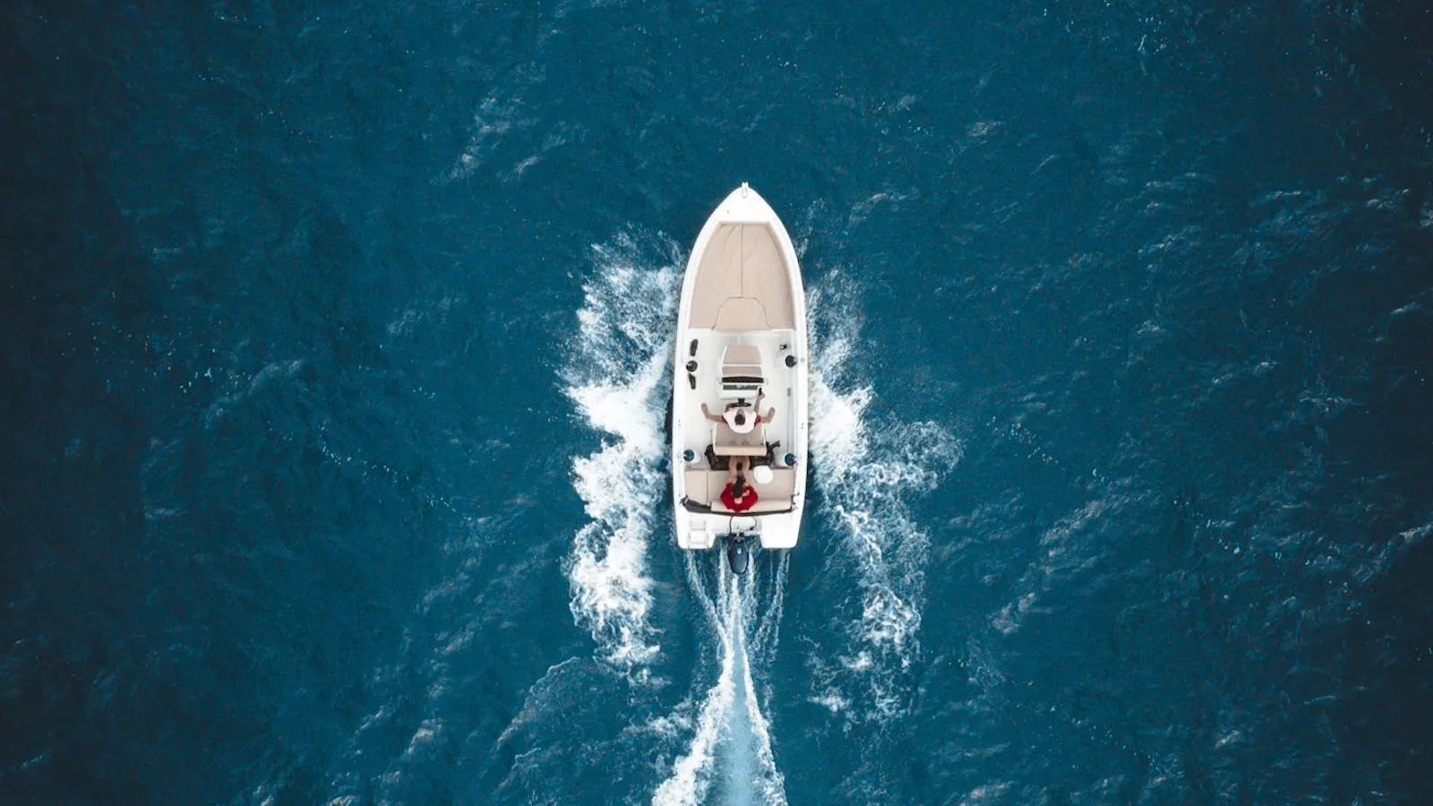 A white speedboat seen from above on the deep blue sea near Tivat